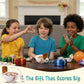 Three children sitting around a table with snacks and presents, smiling and clapping.
